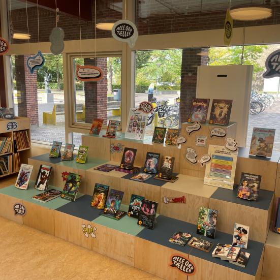 Foto af Solrød Biblioteks udstilling til kampagnen "Tegneserier ER læsning" med bøger, tegneseriegrafikker og talebobler.